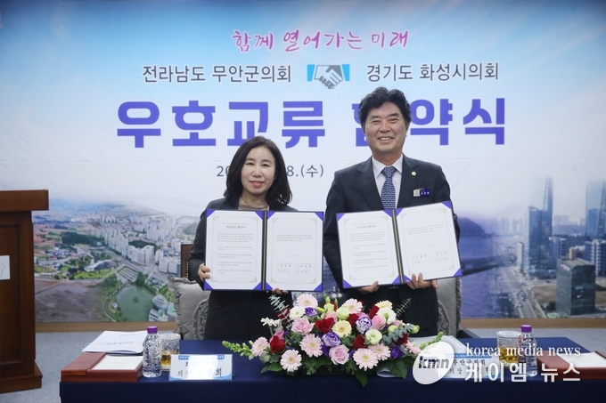 사진/화성시의회(김경희 의장)와 무안군의회(김경현)가 우호교류 협약서 든 모습
