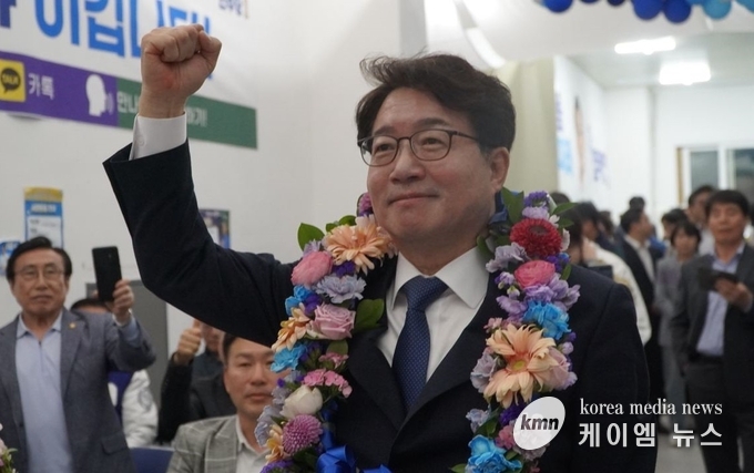 사진/염태영 당선자가 꽃다발을 목에걸고 환호에 답하고있다.