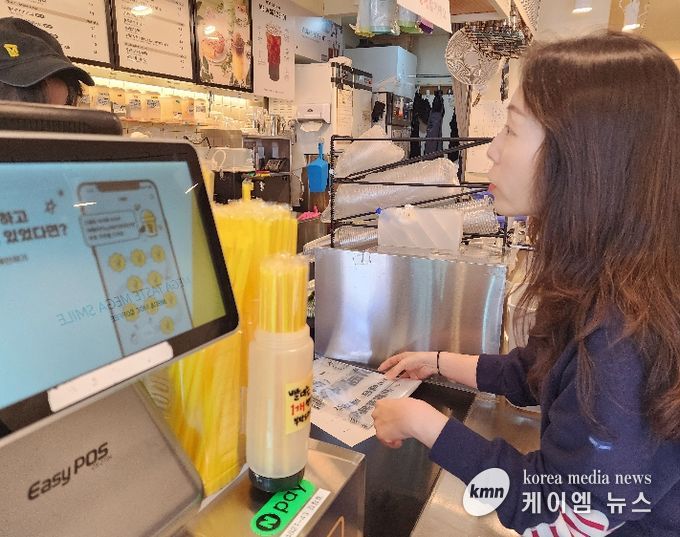 화산동 관계자가 카페를 방문해 종이팩 별도 수거 사업을 홍보하며 전용 수거 봉투를 전달하고 있다